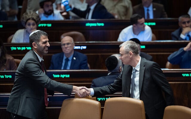 Communications Minister Shlomo Karhi (left) and Justice Minister Yariv Levin shake hands in the Knesset after the coalition's media overhaul law is passed, on July 16, 2026. (Yonatan Sindel/Flash90) Communications Minister Shlomo Karhi (left) and Justice Minister Yariv Levin shake hands in the Knesset after the coalition's media overhaul law is passed, on July 16, 2026. (Yonatan Sindel/Flash90)