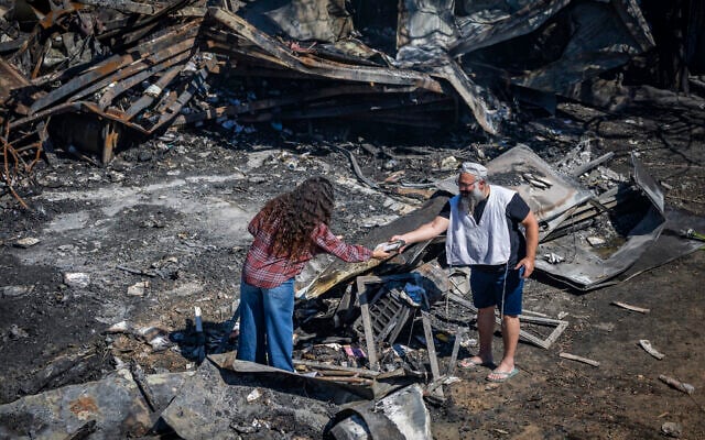 People inspect damage caused by a fire on July 18 in the Israeli settlement of Havat Gilad in the West Bank, seen on July 19, 2026. (Chaim Goldberg/Flash90)