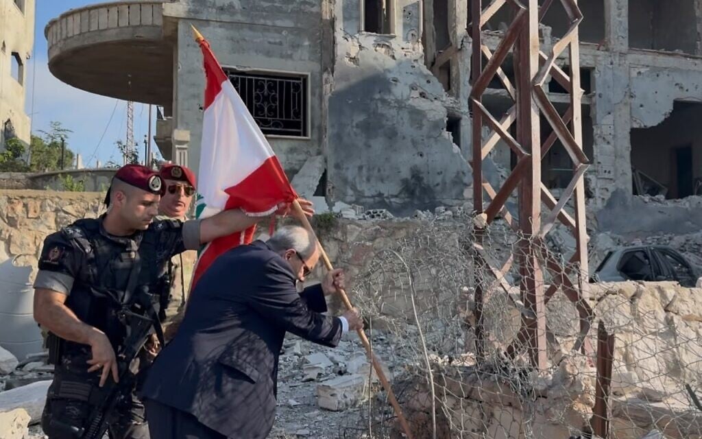 A handout picture released by the office of Lebanese Prime Minister Nawaf Salam shows him placing a national flag  in the village of Zawtar al-Gharbiya on July 22, 2026, after after Israeli troops withdrew. (Office of the Lebanese Prime Minister)