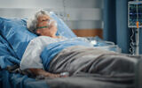 Illustrative image of an elderly woman lying in a hospital bed. (gorodenkoff, iStock by Getty Images)