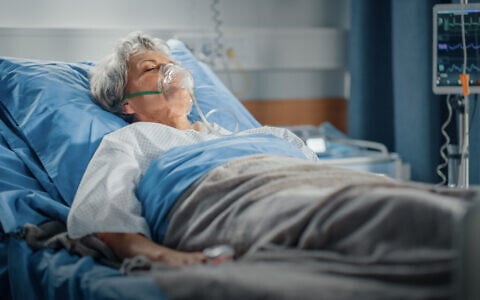 Illustrative image of an elderly woman lying in a hospital bed. (gorodenkoff, iStock by Getty Images)