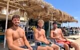 From left to right: Nitzan Eliyahu, Shon Brener, and Omer Maoz tan on the beach in Shavei Zion, Western Galilee, on July 16, 2026. (Diana Bletter/Times of Israel) From left to right: Nitzan Eliyahu, Shon Brener, and Omer Maoz tan on the beach in Shavei Zion, Western Galilee, on July 16, 2026. (Diana Bletter/Times of Israel)