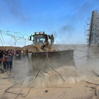Gazans with an earth-mover break through the Israel-Gaza border fence into southern Israel, October 7, 2023. (Mohammed Fayq Abu Mostafa/Reuters)