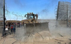 Gazans with an earth-mover break through the Israel-Gaza border fence into southern Israel, October 7, 2023. (Mohammed Fayq Abu Mostafa/Reuters)