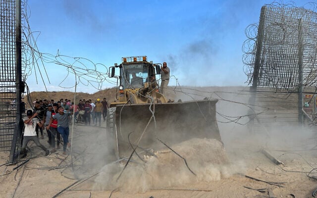 Gazans with an earth-mover break through the Israel-Gaza border fence into southern Israel, October 7, 2023. (Mohammed Fayq Abu Mostafa/Reuters)