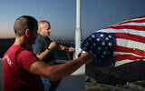 Palestinian-American Loui Ridi, whose home in the West Bank village of in Qusra has been encircled by extremist settlers for more than a week, hangs a US flag with his neighbor, after gaining access to his besieged home, August 17, 2026. (Ammar Awad/Reuters)