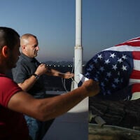 Palestinian-American Loui Ridi, whose home in the West Bank village of in Qusra has been encircled by extremist settlers for more than a week, hangs a US flag with his neighbor, after gaining access to his besieged home, August 17, 2026. (Ammar Awad/Reuters)