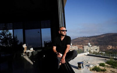 Palestinian-American Loui Abu Ridi looks out the window of his home, which has been encircled by settlers for more than a week, after gaining access to it, in Qusra, West Bank, August 18, 2026. (Ammar Awad/Reuters)