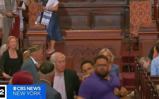 Suspect Larry Montes (wearing blue) seen escorted out of Manhattan’s Central Synagogue after he allegedly attacked worshipers on August 14, 2026. (Screenshot/CBS New York)