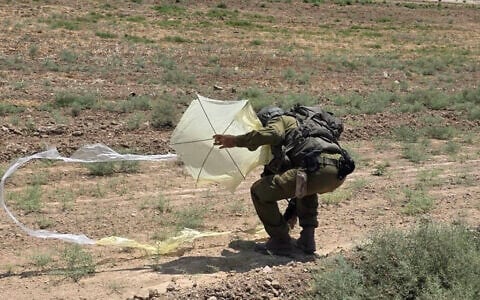 A soldier seen inspecting a kite, apparently flown from the Gaza Strip, that has landed in Kibbutz Nahal Oz, August 22, 2026. (Social media, used in accordance with Clause 27a of the Copyright Law)