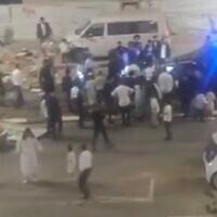 A screenshot of video showing a group of Haredim surrounding a police cruiser on a street that was blocked off to prevent motorists from driving there over Shabbat, August 28, 2026, in Bnei Brak. (X screenshot)
