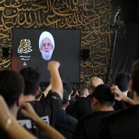 People react as Hezbollah Secretary-General Sheikh Naim Qassem addresses crowds via a screen during the first day of Ashura commemorations at the mausoleum of former Hezbollah leader Hassan Nasrallah in Beirut’s southern suburbs on June 17, 2026. (Anwar Amro/AFP)