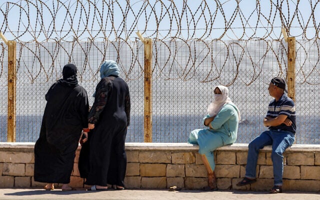 Relatives and friends wait by a fence topped with barbed-wire for the return of people who had previously crossed into Spain’s North African enclave of Ceuta, at Morocco’s Bab Sebta border crossing, on August 2, 2026. (Abdel Majid BZIOUAT/AFP)
