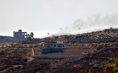A photograph taken from the southern Lebanese village of Chaqra shows an Israeli flag fluttering over the burnt fields of the border village of Mais al-Jabal, burnt during Israeli military operations on August 11, 2026. (Ammar Ammar/AFP)