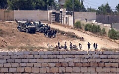 Israeli soldiers stand guard next to settlers (front) in front of the Palestinian houses in the village of Qusra, south of Nablus, in the West Bank, on August 12, 2026. (Zain Jaafar/AFP)