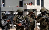 Israeli forces stand in front of the entrance of a Palestinian house besieged by Israeli settlers in the village of Qusra, south of Nablus, in the West Bank, on August 14, 2026. (Jaafar ASHTIYEH/AFP)