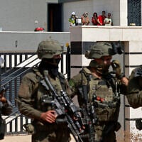 Israeli forces stand in front of the entrance of a Palestinian house besieged by Israeli settlers in the village of Qusra, south of Nablus, in the West Bank, on August 14, 2026. (Jaafar ASHTIYEH/AFP)