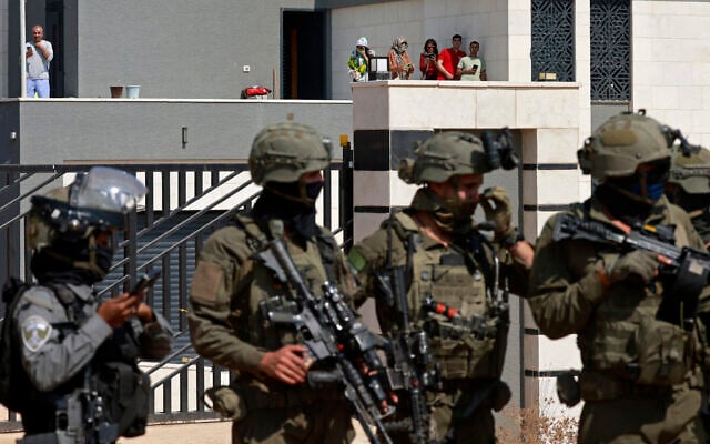 Israeli forces stand in front of the entrance of a Palestinian house besieged by Israeli settlers in the village of Qusra, south of Nablus, in the West Bank, on August 14, 2026. (Jaafar ASHTIYEH/AFP)