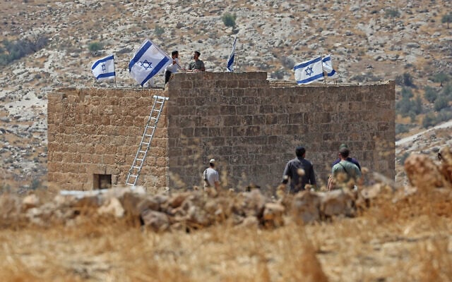 Israeli settlers install flags over a Palestinian house seized by them, in Beit Sahur, south of Bethlehem, in the West Bank on August 14, 2026. (AHMAD GHARABLI/AFP)