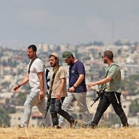 Israeli settlers walk through an open field in Beit Sahur, south of Bethlehem, in the West Bank on August 14, 2026. (AHMAD GHARABLI/AFP)