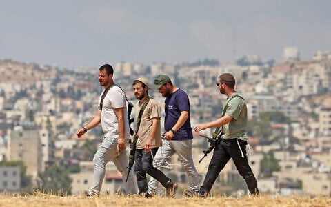 Israeli settlers walk through an open field in Beit Sahur, south of Bethlehem, in the West Bank on August 14, 2026. (AHMAD GHARABLI/AFP)