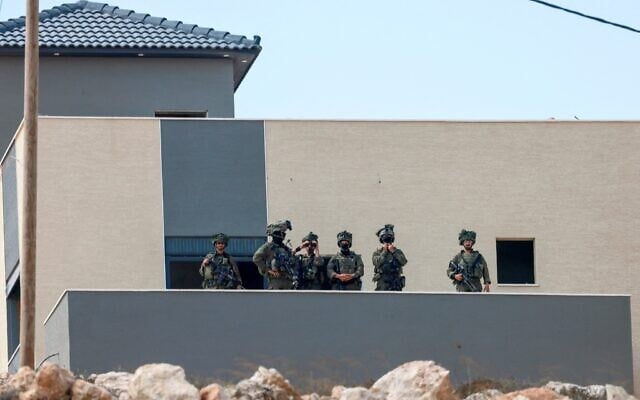 Israeli soldiers take position in a building located adjacent to the home of a Palestinian family besieged by Israeli settlers in the village of Qusra, south of the city Nablus, in the West Bank, on August 14, 2026. (Jaafar ASHTIYEH/AFP)