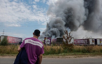A Wildberries emloyee looks at a plume of smoke rising during a fire at Russian e-commerce firm Wildberries’ logistics complex near the town of Podolsk, outside Moscow on August 16, 2026. (Tatyana Makeyeva/AFP)
