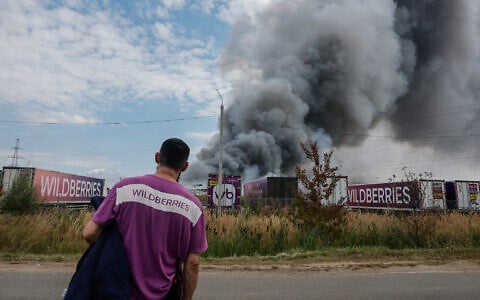 A Wildberries emloyee looks at a plume of smoke rising during a fire at Russian e-commerce firm Wildberries’ logistics complex near the town of Podolsk, outside Moscow on August 16, 2026. (Tatyana Makeyeva/AFP)