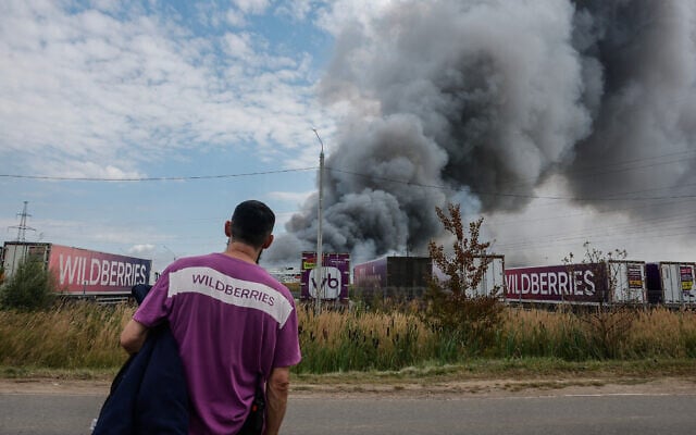 A Wildberries emloyee looks at a plume of smoke rising during a fire at Russian e-commerce firm Wildberries’ logistics complex near the town of Podolsk, outside Moscow on August 16, 2026. (Tatyana Makeyeva/AFP)
