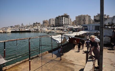 Palestinians stand at a site in Gaza City’s port that was targeted by an Israeli army strike the previous day, on August 19, 2026. (Omar AL-QATTAA/AFP)