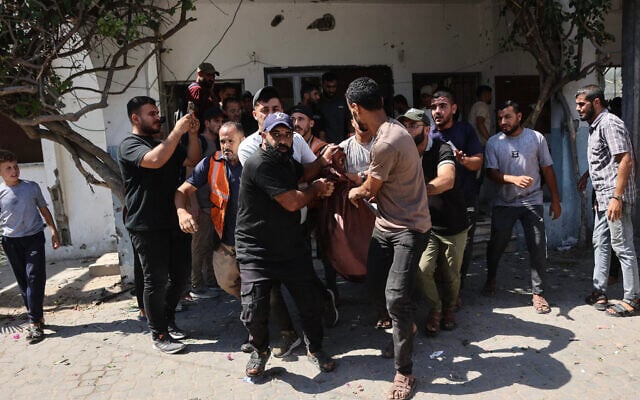 Displaced Palestinians carry victims away from the site of an Israeli strike that targeted police headquarters in Gaza City on August 19, 2026. (Omar AL-QATTAA/AFP)