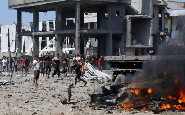 Palestinians gather at the site of a burning truck between the areas of Maghazi and al-Zawayda following an Israeli strike in the central Gaza Strip, August 23, 2026. (Eyad Baba/AFP)