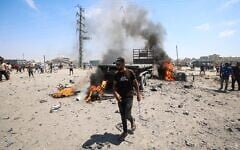 A Palestinian man walks past a burning truck following an Israeli strike, in the area of Maghazi refugee camp, in the central Gaza Strip, on August 23, 2026. (Eyad Baba/AFP)