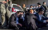 Policemen stand by as ultra-Orthodox men block a road during a protest against conscription into the Israel Defense Forces, in Bnei Brak on August 24, 2026. (Ilia YEFIMOVICH/AFP)