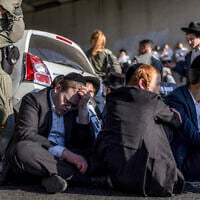 Policemen stand by as ultra-Orthodox men block a road during a protest against conscription into the Israel Defense Forces, in Bnei Brak on August 24, 2026. (Ilia YEFIMOVICH/AFP)