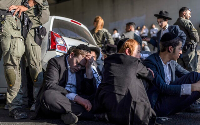 Policemen stand by as ultra-Orthodox men block a road during a protest against conscription into the Israel Defense Forces, in Bnei Brak on August 24, 2026. (Ilia YEFIMOVICH/AFP)