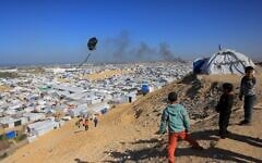 (FILE) Boys fly a kite against the backdrop of smoke rising from the Gath shelter, that houses displaced Palestinians, after an Israeli airstrike in the west of Khan Younis, southern Gaza Strip on January 31, 2026. (Bashar Taleb/AFP)