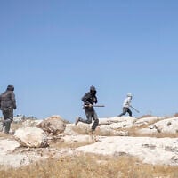 Israeli settlers, holding sticks, arrive to confront left-wing activists at an Israeli outpost in the Palestinian village of Jannatah, south of Bethlehem, on August 25, 2026. (ilia YEFIMOVICH/AFP)