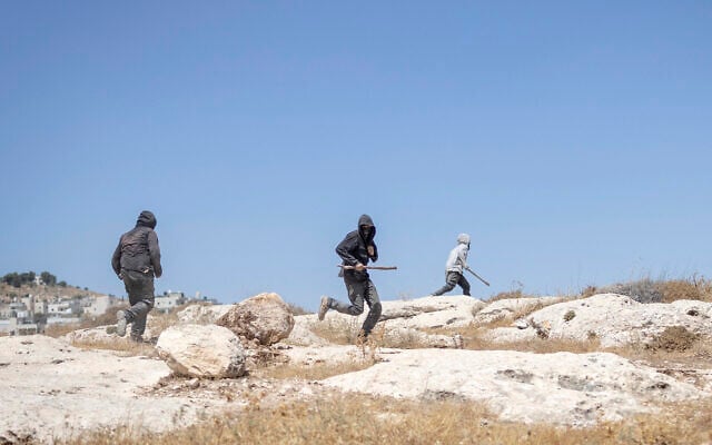 Israeli settlers, holding sticks, arrive to confront left-wing activists at an Israeli outpost in the Palestinian village of Jannatah, south of Bethlehem, on August 25, 2026. (ilia YEFIMOVICH/AFP)