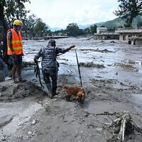 A member of the security forces and his sniffer dog search for survivors following flash floods at Trishuli in Nepal’s Nuwakot district on August 27, 2026. (Prakash MATHEMA/AFP)