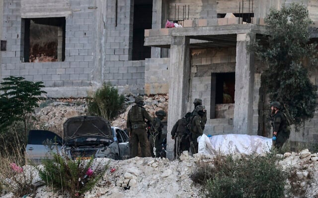 Israeli soldiers remove the body of a Palestinian killed in an air strike from a house under construction, on the western outskirts of the northern city of Jenin, in the West Bank on August 28, 2026. (Jaafar ASHTIYEH/AFP)