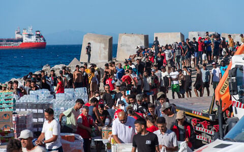 Migrants queue for a Red Cross food distribution at the Trampolin beach in Ceuta on August 28, 2026. (Antonio Sempere/AFP)