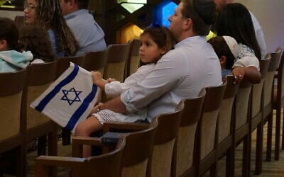 A family with Israel flags attends Shabbat services at Temple Beth Sholom in Miami Beach, Fla., on October 13, 2023. (AP Photo/Giovanna Dell’Orto)
