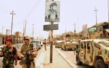 US and Iraqi troops pass a poster of Muqtada al-Sadr, evidence of continued support for the anti-American cleric and his Mahdi Army militia, in Basra, Iraq, on June 10, 2008. (AP Photo/Kim Gamel)
