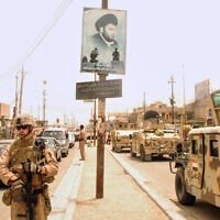 US and Iraqi troops pass a poster of Muqtada al-Sadr, evidence of continued support for the anti-American cleric and his Mahdi Army militia, in Basra, Iraq, on June 10, 2008. (AP Photo/Kim Gamel)
