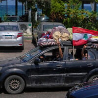 A displaced family with their belongings, wave a Lebanese flag as they return to their village, following a ceasefire between Israel and Hezbollah in the southern port city of Sidon, Lebanon, June 23, 2026. (AP Photo/Mohammed Zaatari)