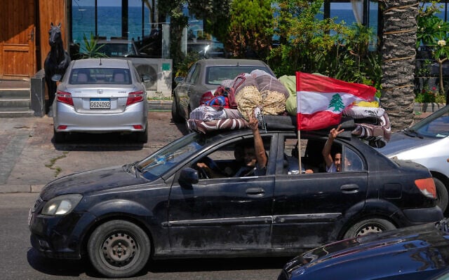 A displaced family with their belongings, wave a Lebanese flag as they return to their village, following a ceasefire between Israel and Hezbollah in the southern port city of Sidon, Lebanon, June 23, 2026. (AP Photo/Mohammed Zaatari)