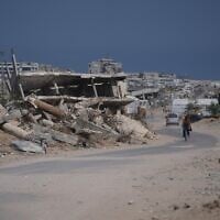 Illustrative: A Palestinian man rides his bicycle by the rubble of buildings that were destroyed during the Israel Hamas war, in southern Gaza Strip, July 31, 2026. (AP/Abdel Kareem Hana)