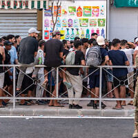 Migrants wait for a shop to open so they can buy food after crossing from Morocco into the Spanish enclave of Ceuta, July 31, 2026. (AP Photo/Antonio Sempere)