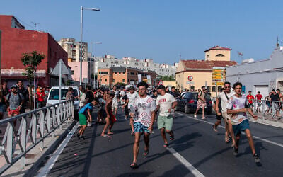 Migrants run from Spanish police officers after crossing from Morocco into the Spanish enclave of Ceuta, July 31, 2026. (AP Photo/Antonio Sempere)